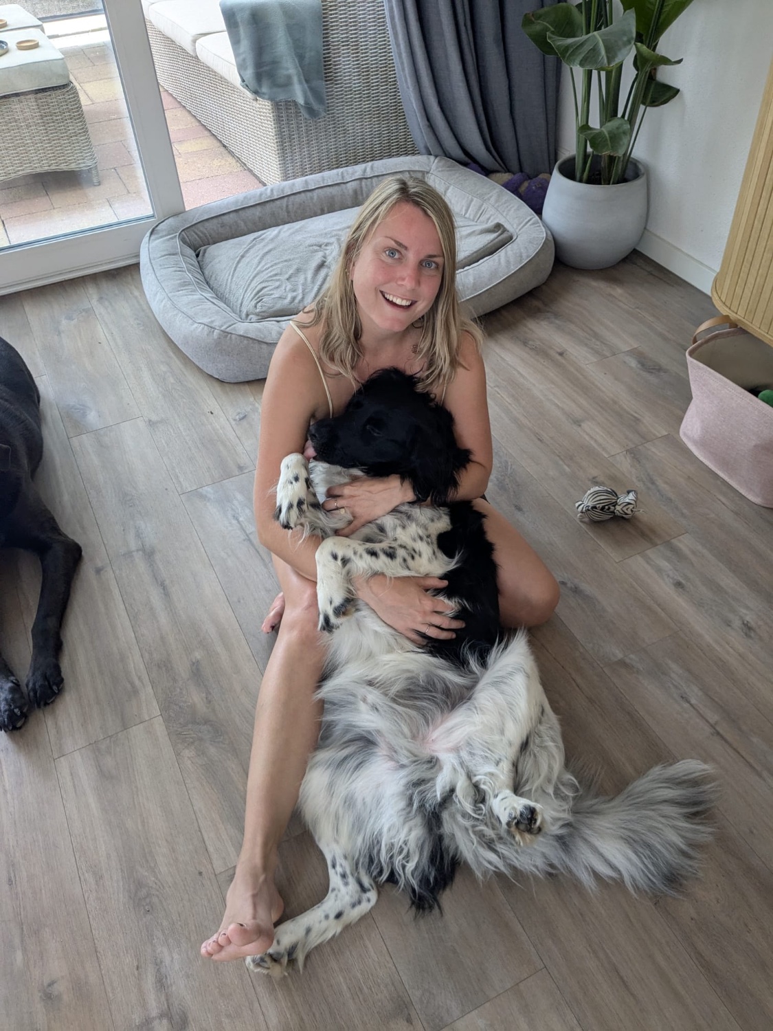 Kelly knuffelt een zwart-witte hond binnenshuis